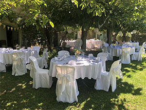 tables et chaises avec nappe blanches dréssées par l'occitane traiteur dans un jardin